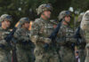 Group of soldiers in camouflage uniforms marching in formation during a military parade