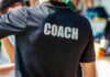 Back view of a person wearing a black shirt with the word COACH printed on it