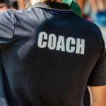 Back view of a person wearing a black shirt with the word COACH printed on it