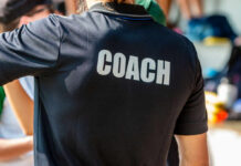 Back view of a person wearing a black shirt with the word COACH printed on it