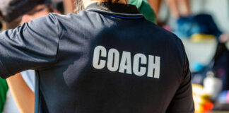 Back view of a person wearing a black shirt with the word COACH printed on it
