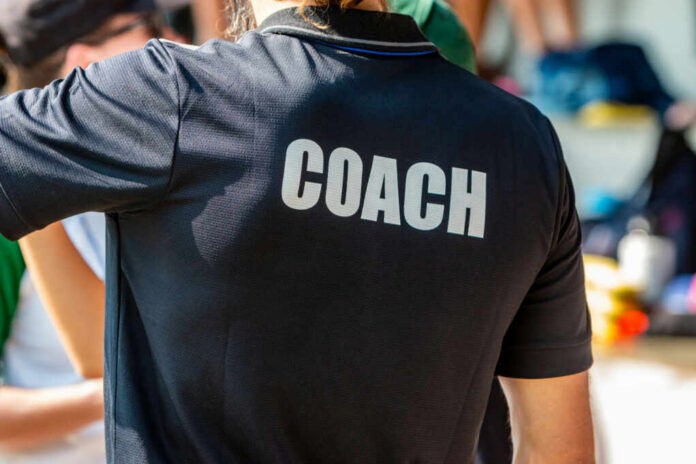 shutterstock1622062555jpg Back view of a person wearing a black shirt with the word COACH printed on it