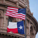 American and Texas flags flying in front of a historic government building