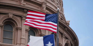 American and Texas flags flying in front of a historic government building