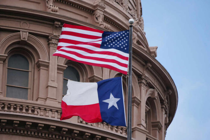 American and Texas flags flying in front of a historic government building