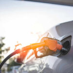 A fuel nozzle inserted into a cars gas tank during sunset