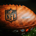 Close-up of an official NFL football with team logos and leather texture