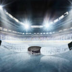 Close-up of a hockey puck on the ice with a hockey stick in the foreground