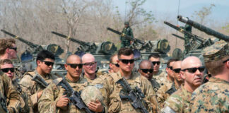 Group of military personnel in camouflage uniforms standing with weapons during a training exercise