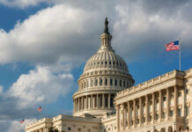 The U.S. Capitol building with a dome and an American flag under a cloudy sky