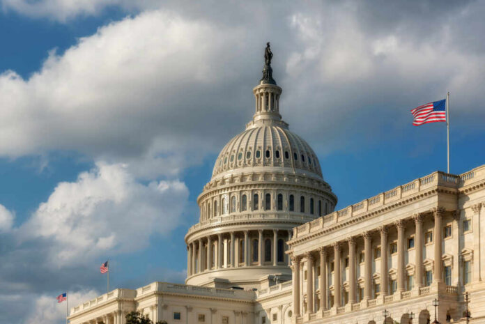 The U.S. Capitol building with a dome and an American flag under a cloudy sky
