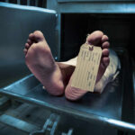 Feet of a deceased person on a metal table with an identification tag
