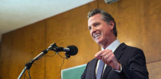 A man in a suit delivering a speech at a podium with microphones