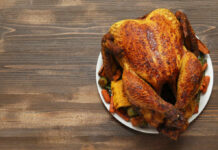 A beautifully roasted turkey served with assorted vegetables on a white plate