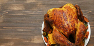 A beautifully roasted turkey served with assorted vegetables on a white plate