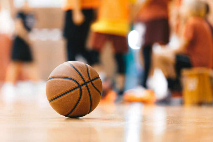 shutterstock2427182761jpg A basketball resting on the gym floor with players blurred in the background
