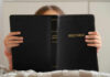 Child holding a black Holy Bible in front of their face