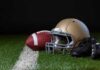 A football helmet, a football, and cleats on a field