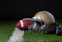 A football helmet, a football, and cleats on a field