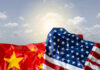 Crumpled flags of the United States and China against a cloudy sky