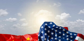 Crumpled flags of the United States and China against a cloudy sky
