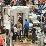 Busy airport security checkpoint with passengers being screened
