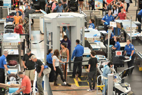 Busy airport security checkpoint with passengers being screened