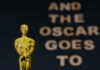 Close-up of a golden Oscar statuette with text in the background
