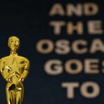 Close-up of a golden Oscar statuette with text in the background