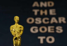 Close-up of a golden Oscar statuette with text in the background