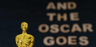 Close-up of a golden Oscar statuette with text in the background