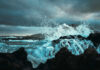 Waves crashing against rocks under a cloudy sky