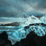 Waves crashing against rocks under a cloudy sky