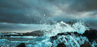 Waves crashing against rocks under a cloudy sky