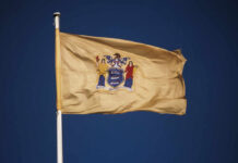 New Jersey state flag waving against a clear blue sky