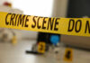 Yellow crime scene tape with evidence markers in a room