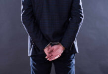 A man in a suit with hands cuffed behind his back