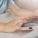 Childs hands interacting with a tablet on a table
