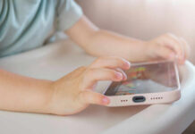 Childs hands interacting with a tablet on a table