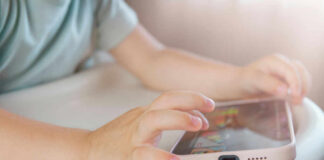 Childs hands interacting with a tablet on a table