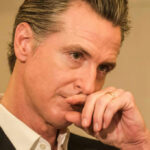 Close-up of a man in a suit with a thoughtful expression, hand on chin