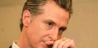 Close-up of a man in a suit with a thoughtful expression, hand on chin