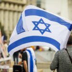 Person holding an Israeli flag at a public demonstration