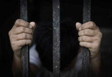 A childs hands gripping prison bars, conveying a sense of confinement and distress