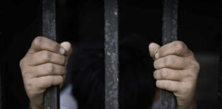 A childs hands gripping prison bars, conveying a sense of confinement and distress