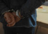 Hands behind back in handcuffs, indicating an arrest