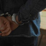 Hands behind back in handcuffs, indicating an arrest