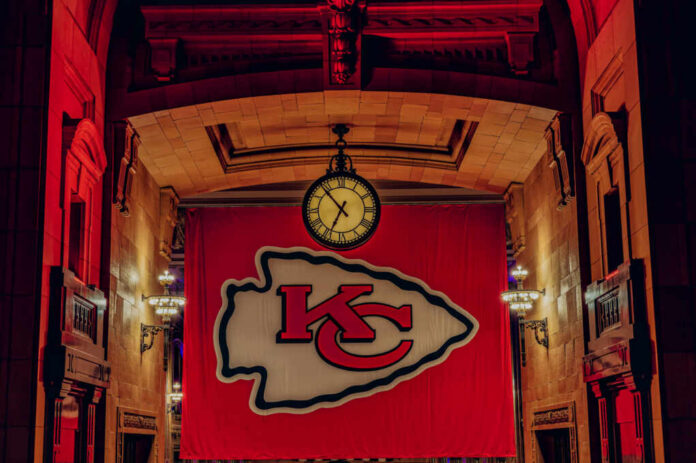 shutterstock_2478636957.jpg Large Kansas City Chiefs banner with a clock in a historic indoor setting