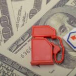 Red fuel pump toy next to hundred dollar bills