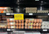 Egg cartons on a supermarket shelf with a sign indicating limited supply